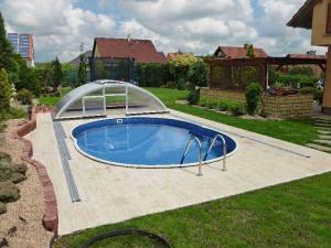 obloukové zastřešení bazénu s dvířky odsunuté za bazén